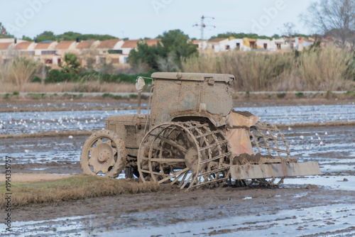 Foto tractor lleno de barro con ruedas metalicas trajando dentro de un arrozal del sa