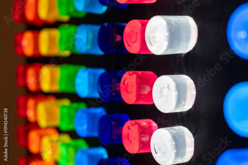 A black light box with a black background and rows of colorful lite pegs. The rows of pegs include blue, white, red, green, yellow, orange, and red. The pegs are round plastic tubes.