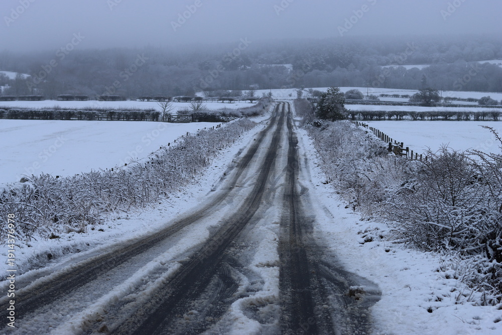 Obraz premium Snow covered countryside road in winter