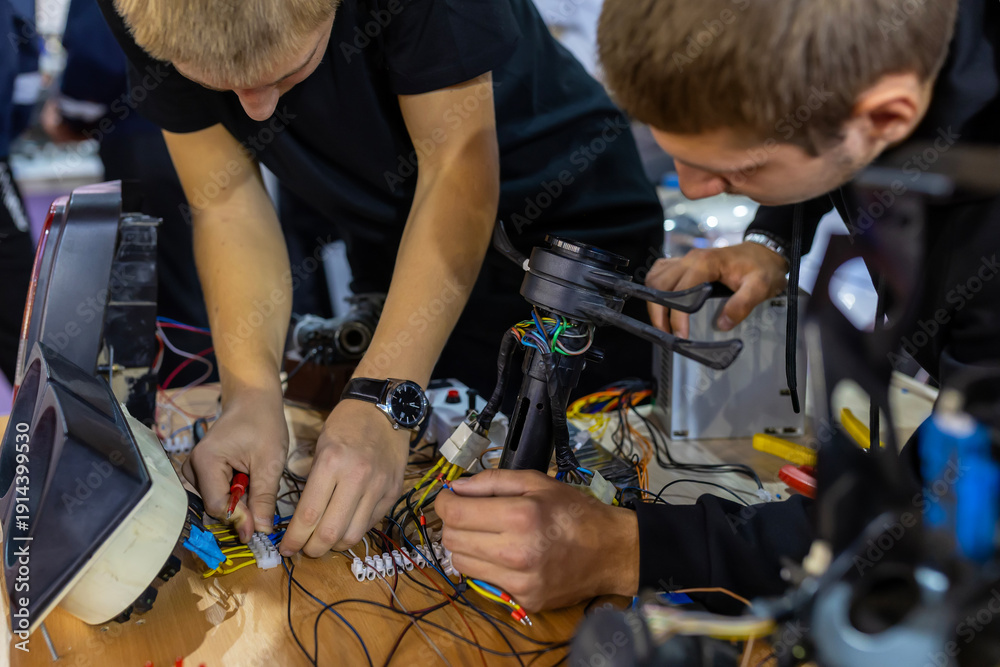 Obraz premium Young men connecting intricate wiring during an electronics workshop