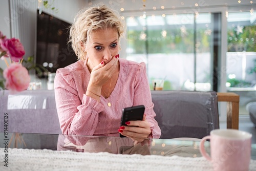 Wallpaper Mural Woman feeling shock and bad news on smartphone at home Torontodigital.ca