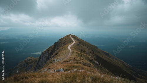 Hiking Trail on Mountain Ridge With Cloudy Sky Above and Distant Hills Far Away