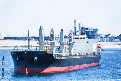 Bild auf Leinwand Close-up view of a general cargo vessel anchored off the coast of Chile with shoreline and industrial infrastructure visible in the background