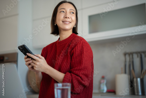 Young woman smiling holding smartphone looking away