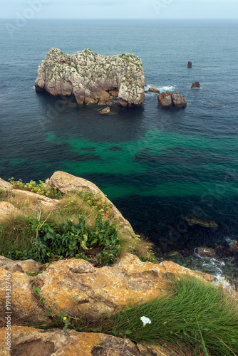 Coastal view with rock formations in the sea, near Somocuevas Beach, in the Costa Quebrada Geopark, in Liencres, Cantabria, Spain.