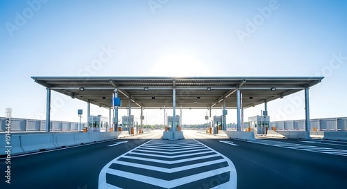 Empty highway toll booth plaza or border checkpoint with symmetrical lanes and a clear blue sky.