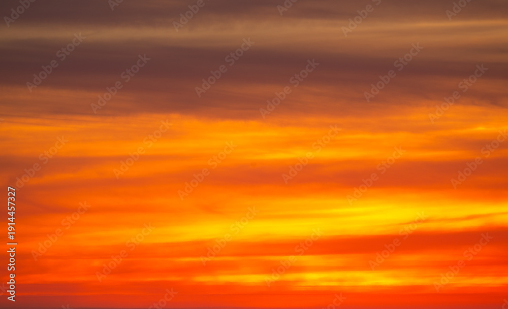 Fototapeta premium Orange and pink sunset sky with soft glowing clouds. Warm golden gradient background with smooth pastel tones and tranquil evening atmosphere. Natural abstract sky texture