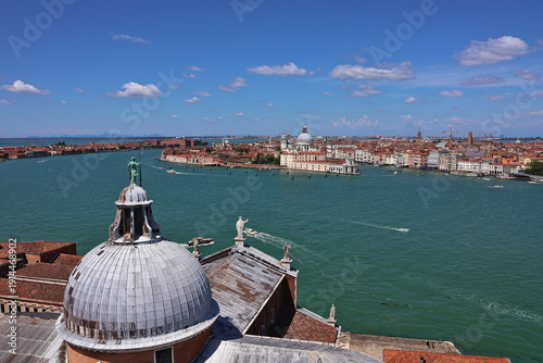 Panoramic view of Venice from San Giorgio Maggiore over historic domes and statues to boats on the Venetian Lagoon; iconic Italian cityscape with iconic architecture, scenic waterfront, grand canal