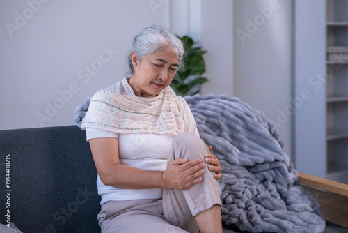 Canvas Print Senior woman feeling knee pain on couch