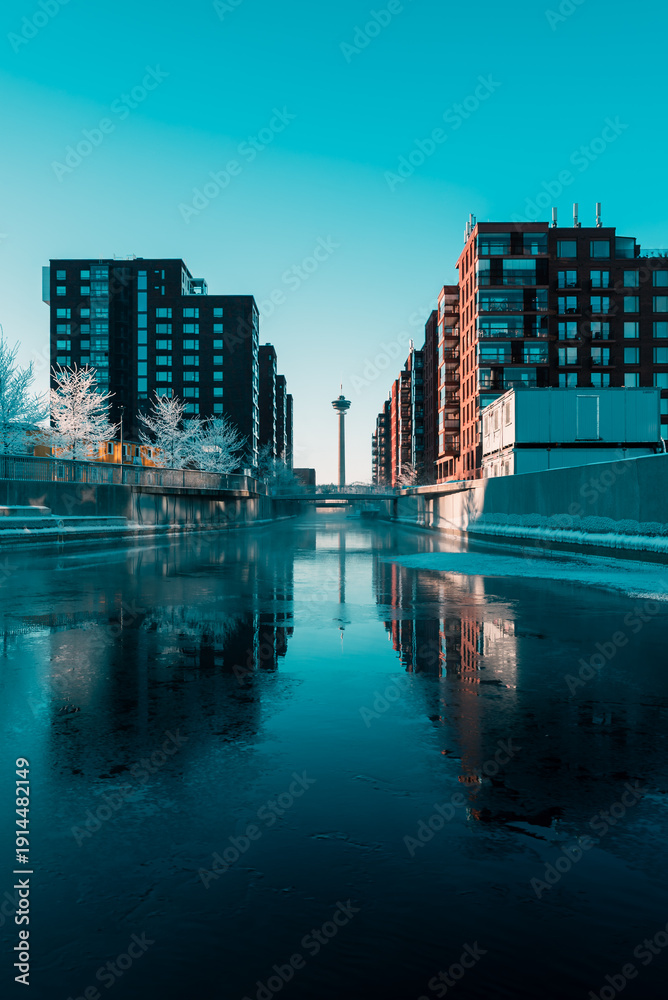 Fototapeta premium Cinematic winter canal between modern buildings in Tampere, Finland