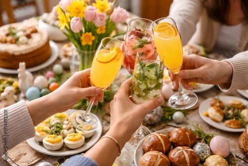 Easter brunch celebration with friends toasting festive drinks at beautifully decorated table featuring colorful eggs, flowers, traditional food. holiday gathering, festive decor, friendship.