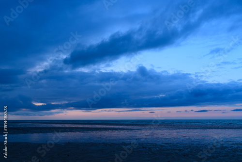 Canvastavla Moody twilight clouds stretch across the sky above the calm, reflective waters of the English Channel, with soft blue and pink hues creating a tranquil seascape at low tide