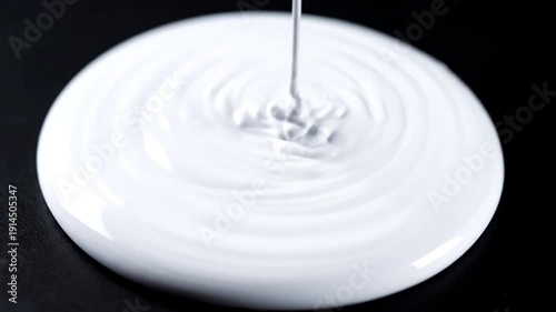 Droplet of milk falling into a white plate creating ripples.