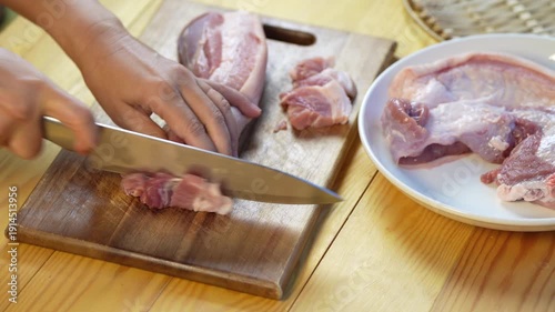 Hands slicing fresh raw pork belly on wooden cutting board in home kitchen, food preparation process for cooking meal, close up culinary preparation and ingredient handling