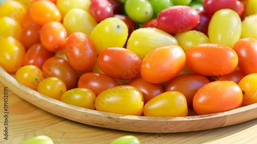 Colorful premium cherry tomatoes in red, yellow, orange and green tones filling the frame, fresh organic produce concept for healthy eating, vegan diet and farm to table food on wooden table.