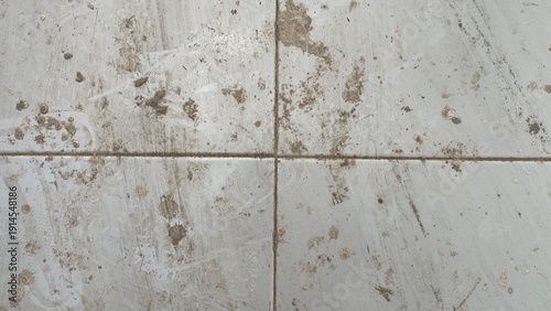 Fényképezés Dirty white floor tiles covered in muddy stains and grime, showcasing a messy and unhygienic surface in need of cleaning