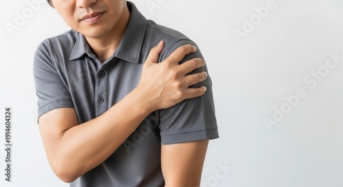 A man clutching his shoulder in pain against a plain white background