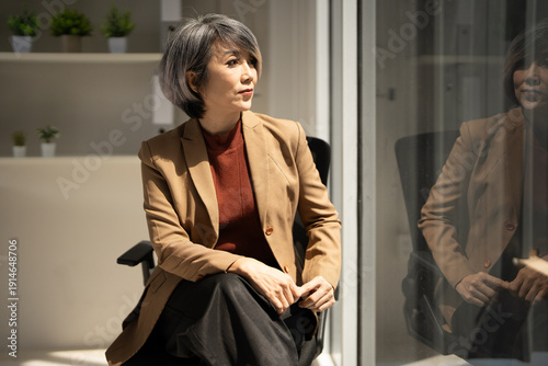 Mature senior business woman at work looking away dreaming of future successful career. lost in thoughts visualizing, business vision concept.