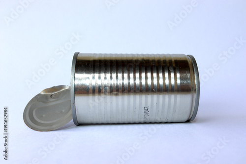 An old can with its lid, placed horizontally against white background, close-up shot.