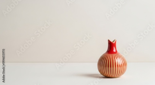A decorative ceramic pomegranate-shaped vase with red and orange stripes