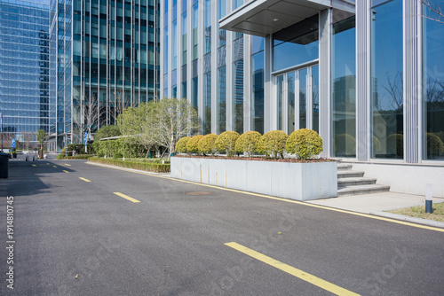 Bilde på lerret Empty asphalt road in front of a modern glass facade office building during dayt
