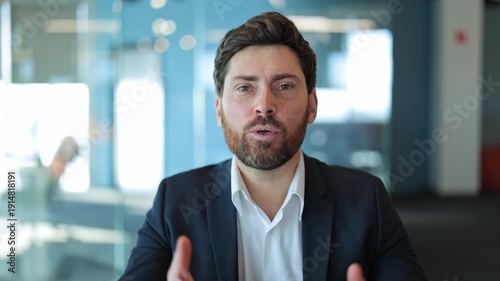 Professional businessman confidently conveys ideas. Engaging, clear communication with focused messages. Expresses dedication and seriousness within modern office setting.