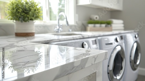 Modern utility room glossy white marble countertops, sink, and front-load laundry machines
