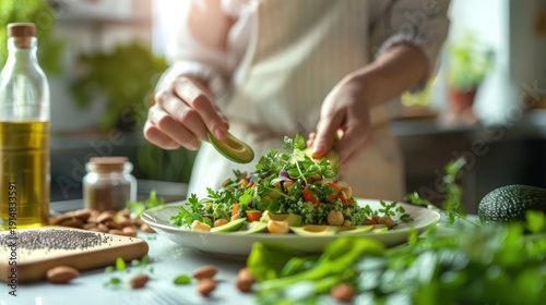 Person's hands add avocado to a vibrant, fresh salad in a sunny kitchen setting