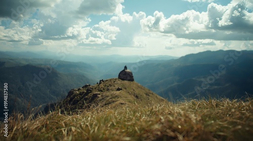 Person on hilltop overlooking mountain range under cloudy sky