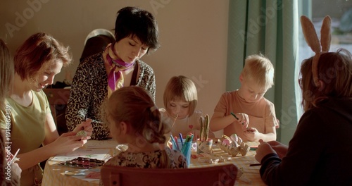 A group crafting activity takes place with both adults and children happily engaged around a table filled with various art supplies and materials