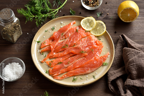 Slices of salted salmon on plate on dark wooden table