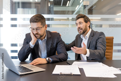 Obraz na płótnie Upset businessman in a suit having a conversation with a colleague reassuring hi