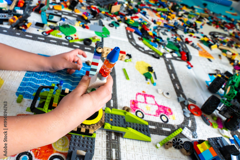 Fototapeta premium Child Playing With Lego Bricks Building Rocketship On Colorful Play Mat