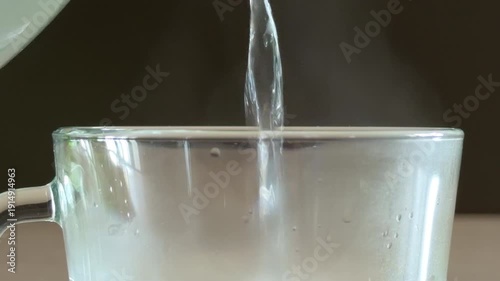 Wallpaper Mural Hot water streams from a kettle into a clear glass mug. The liquid creates a rhythmic sloshing and splashing sound as the cup fills. Torontodigital.ca