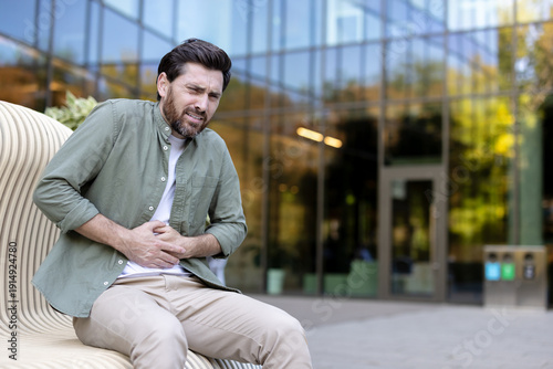 Εκτύπωση καμβά Man experiencing acute stomach pain and discomfort, holding his abdomen with a g