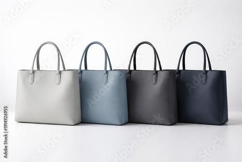 Four tote bags in various colors are lined up on a white surface showing different styles and designs for shoppers to observe