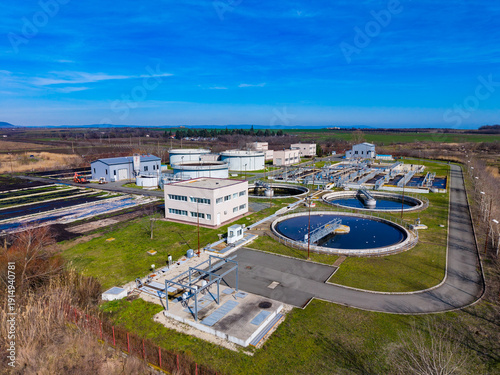 Water treatment plant operates in the rural area with large circular tanks and buildings during a clear day in early spring