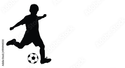 A young soccer player dynamically kicks a ball captured in silhouette