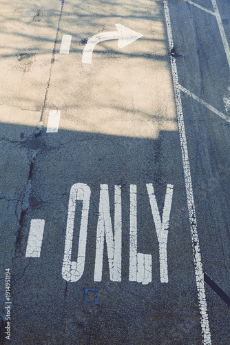 Road sign indicating right turn only in a city street context during daytime with clear markings and shadows across the pavement