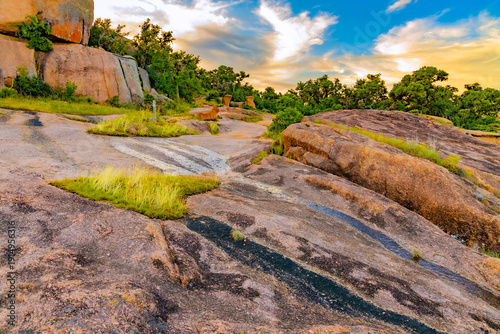 Foto A winding dirt path leads through the scrub brush and mesquite trees at the base of the granite formations in the Texas Hill Country