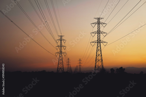 Foto Silhouette of high-voltage electric transmission towers and power lines against a beautiful sunset sky with orange and purple hues