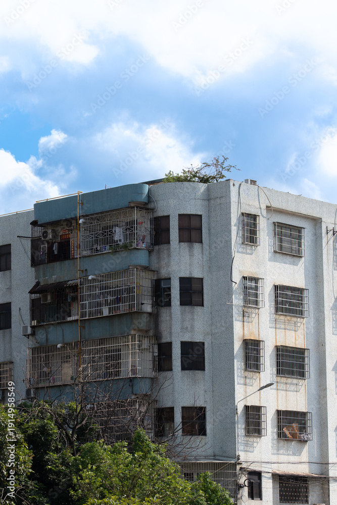 Fototapeta premium Dilapidated multi-story apartment building with rusted balconies under cloudy sky