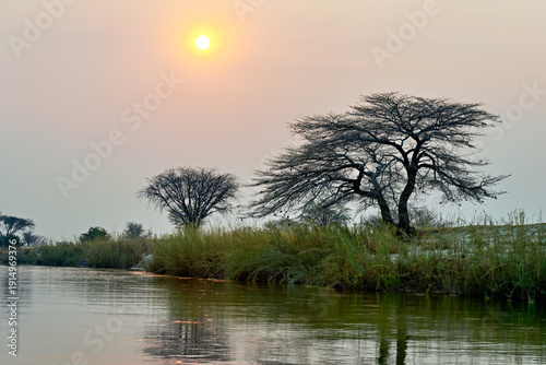 Banks of Okavango River at dusk in Namibia with setting sun