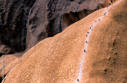 Obraz na plátně Hikers ascend Uluru using a chain ladder in Australia.