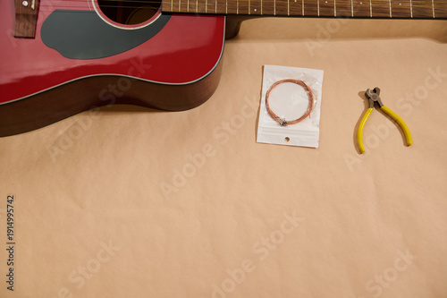 Red Acoustic Guitar With Replacement Strings And Pliers For Maintenance And Repair