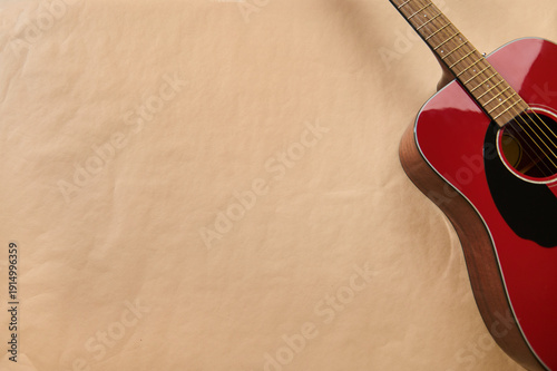 Fotografie Red Acoustic Guitar With Strings For Maintenance And Repair On Brown Paper Backg