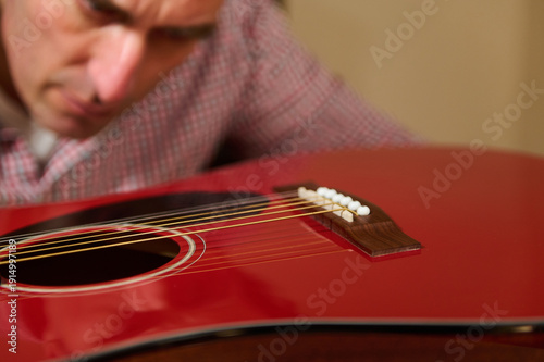 Man Adjusting Guitar Strings During Acoustic Guitar Maintenance And Repair