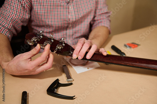 Man Changing Guitar Strings and Tuning Headstock During Guitar Maintenance and Repair