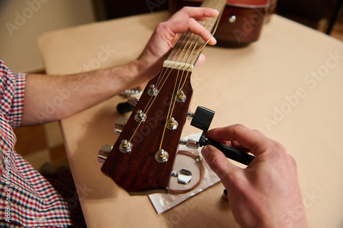 Foto Man Tuning Acoustic Guitar Headstock With Wrench During String Change And Mainte