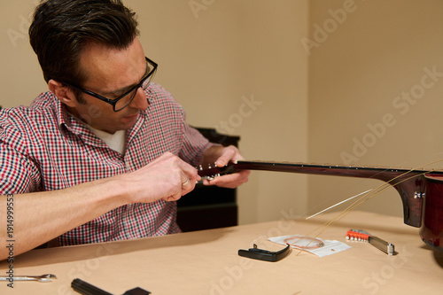 Fotografie Man Replacing Guitar Strings at Table — Guitar Maintenance and Repair by Focused